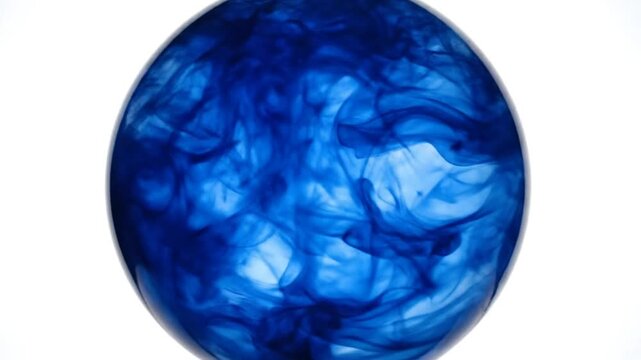 Abstract slow motion view of blue ink swirling inside a transparent egg shape against white background