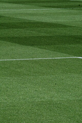 Obraz premium Well-Maintained Football Stadium Pitch with Striped Grass Under Clear Blue Sky