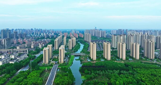 Aerial view of modern residential apartment buildings and lush green urban landscape with a river flowing through a contemporary city district.