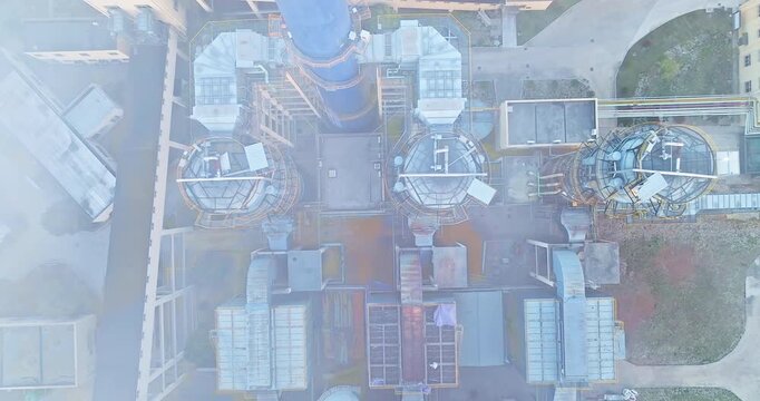 Aerial top view of industrial power plant infrastructure with large blue smokestack and complex ductwork system in manufacturing facility complex.