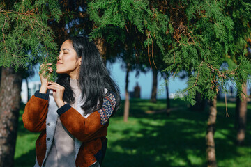 Naklejka premium Nature, outdoors, greenery, leaves, fragrance, breeze, park, relaxation, serenity, woman exploring leaves in a sunlit park, capturing fragrance and breeze as she relaxes among trees, enjoying