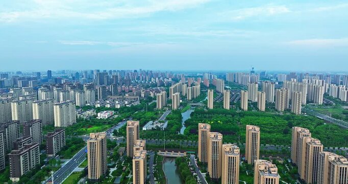 Modern residential district with tall apartment buildings and green park belt in urban development zone seen from high angle aerial view.