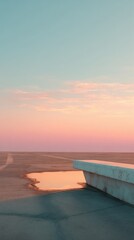 Fototapeta premium Minimal concrete pier extending into calm foggy water with soft pink sunrise reflection in still surface.