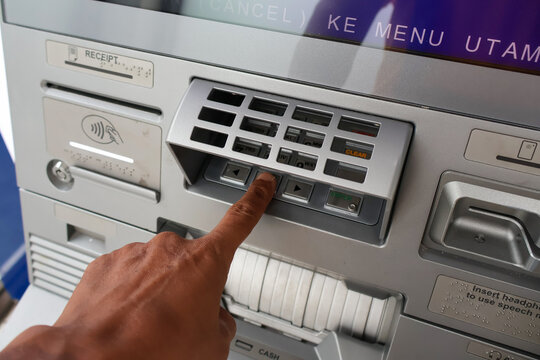 ​A person's hand typing a PIN code on an ATM machine keypad at a bank to authorize a secure financial transaction and access banking services safely.