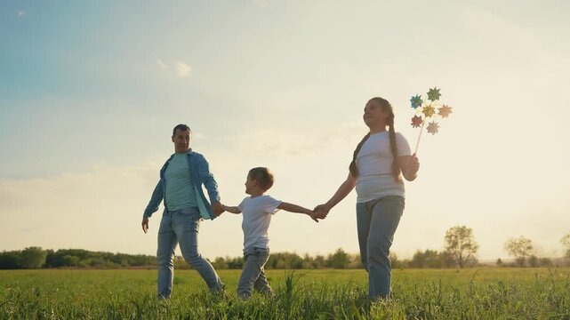 Family walking in field. Silhouette of family holding hands in lifestyle a park. A dad and his children are walking toy. A family strolling through a field.