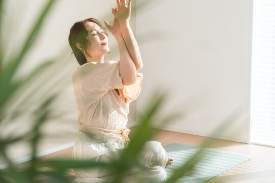 A woman doing yoga in her living room (Eagle Pose, relaxation, healthcare, meditation)