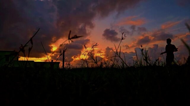 Silhouette of a cricket player playing a shot during dramatic sunset in India. Slow motion sports scene with golden sky, outdoor field, and action moment, ideal for cricket, sports, and lifestyle.