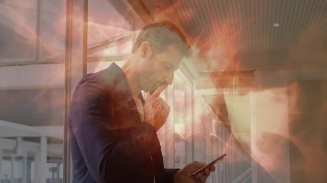 Exec by glass wall glancing at phone and tapping checking mail, warm effect blending with man