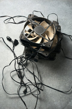 pile of dusty black plastic computer cooling fans with tangled wires and frames, top view on grey textured surface, electronic hardware waste and recycling concept