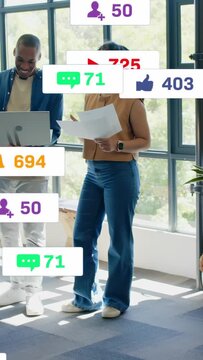 Vertical video: Woman reading docs while man on laptop causing social notifs rising or falling on KP