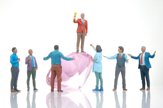 Celebration of success with a group of figures around a large pink gem in an indoor setting