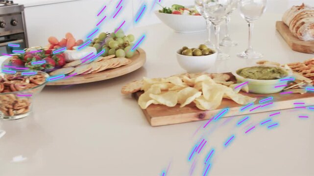 Camera panning right, food spread revealing cheese, glasses for party, blue-purple streaks sweeping