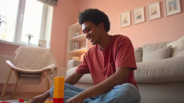 Black man building colorful block tower on rug in sunlit living room, arranging multicolored toy blocks with focused concentration, casual clothes, sitting crosslegged near couch,