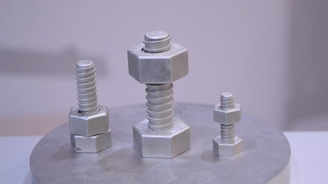 Object printed on 3D printer from metal powder by laser sintering closeup. Selective laser melting technology. Woman finger twisting metal detail on thread created. New modern 3D printing technologies