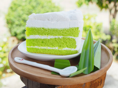 A pandan cake topped with young coconut custard is placed on a plate. It has a vibrant green color, looks appetizing, and tastes wonderfully sweet and soft.