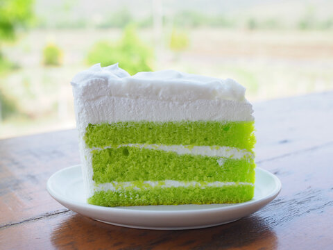 A pandan cake topped with young coconut custard is placed on a plate. It has a vibrant green color, looks appetizing, and tastes wonderfully sweet and soft.