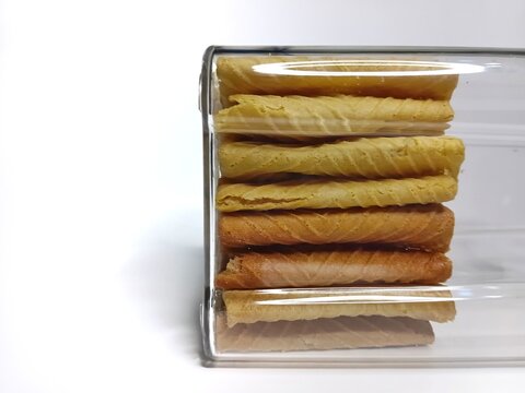 Stacked crispy egg rolls (gapit) with caramelized sugar coating. A sweet and savory traditional Indonesian snack isolated on white background.