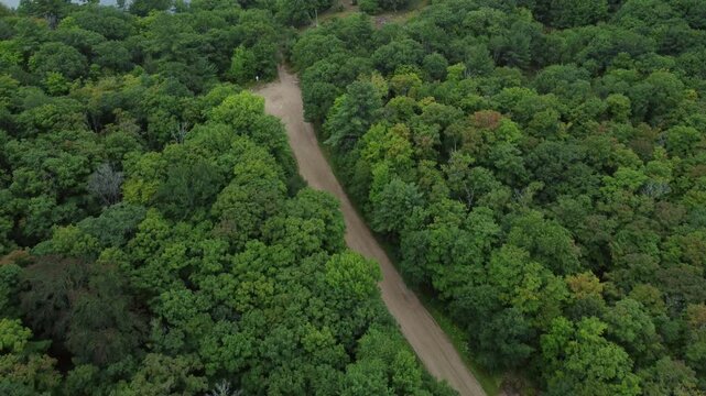 Aerial over wilderness crown land in Tory Hill, Highlands East, Ontario, Canada. Flying over a path towards a boat launch on Buckskin Lake on a summer afternoon.