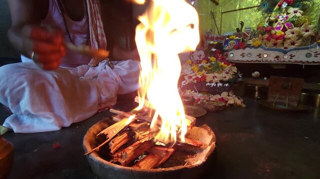 Hindu priest performing havan ritual with sacred fire and wooden offerings. Traditional yagya ceremony symbolizing spirituality, devotion, and Vedic rituals in Indian culture.