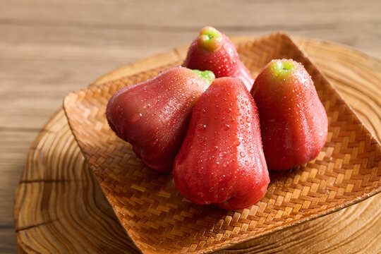 Fresh Red Wax Apples on Woven Bamboo Plate, Vintage Wood Grain Background, Natural Lighting