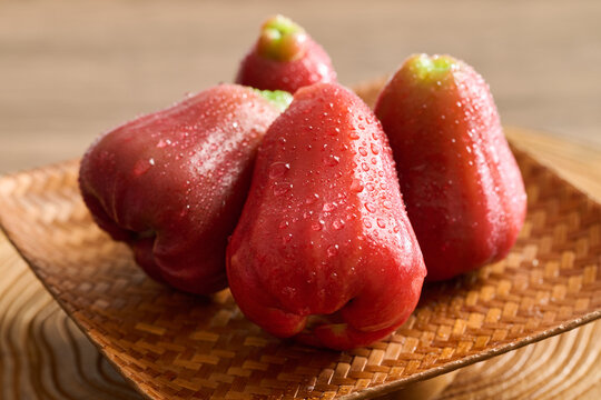 Fresh Red Wax Apples on Woven Bamboo Plate, Vintage Wood Grain Background, Natural Lighting