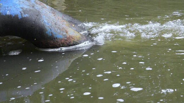 industrial drainage pipe discharging waste water into a natural pond
