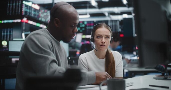 Diverse Professional Team Reviewing Investment Data in Global Brokerage Firm. Mentor Gestures Towards Advanced Financial Indices, Woman Engages in Discussion. Concept of Synergy of Multicultural Team.