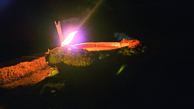 Close-up of burning diya oil lamp glowing in darkness with soft flame. Traditional Indian Diwali lighting symbolizing hope, spirituality, and peace, ideal for festival, religion themes.