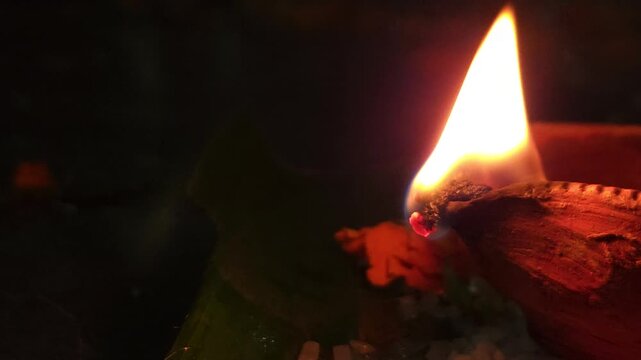 Close-up of burning diya oil lamp glowing in darkness with soft flame. Traditional Indian Diwali lighting symbolizing hope, spirituality, and peace, ideal for festival, religion themes.
