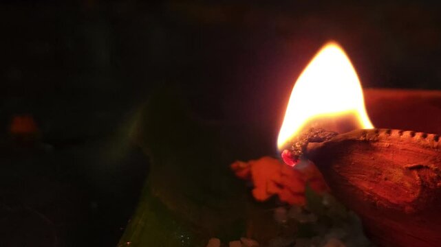 Close-up of burning diya oil lamp glowing in darkness with soft flame. Traditional Indian Diwali lighting symbolizing hope, spirituality, and peace, ideal for festival, religion themes.