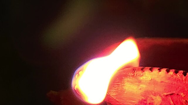 Close-up of burning diya oil lamp glowing in darkness with soft flame. Traditional Indian Diwali lighting symbolizing hope, spirituality, and peace, ideal for festival, religion themes.