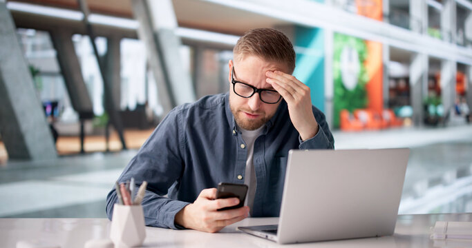 Man Worriedly Examines Smartphone For Payment Problems