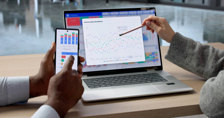 Analyzing Financial Data On Laptop, Marketer And Analyst Discuss Charts