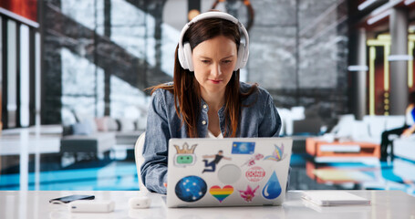 Young Woman With Headphones Engaged In Online Learning On Laptop