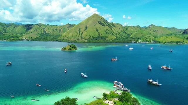 Epic aerial drone footage capturing a tropical island paradise with crystal clear turquoise waters, pristine white sand beaches, and traditional Indonesian phinisi boats sailing peacefully. The camera