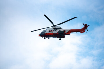 Rescue helicopter emergency helicopter red helicopter search and rescue flying aircraft rotor blade sky background cloud sky aviation air patrol rescue helicopter flying blue cloudy sky during