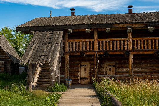 The impressive wooden walls of a reconstructed Old Slavic fortress, made of round, hewn logs. Old barracks and boyar chambers. A bright, sunny day.