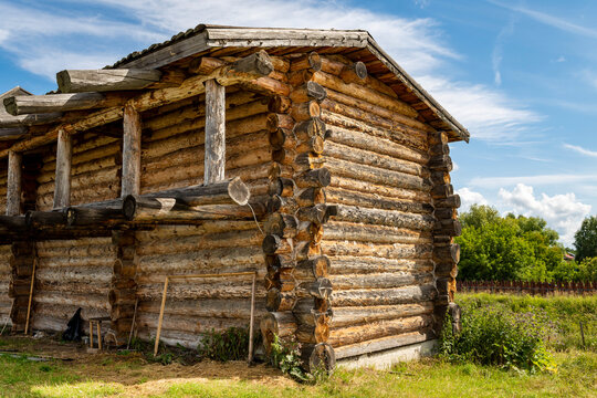 The impressive wooden walls of a reconstructed Old Slavic fortress, made of round, hewn logs. Old barracks and boyar chambers. A bright, sunny day.