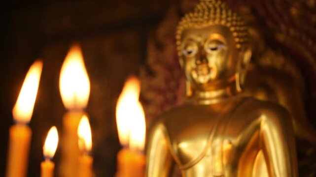 Golden Buddha Statue in Dimly Lit Shrine with Flickering Candles
