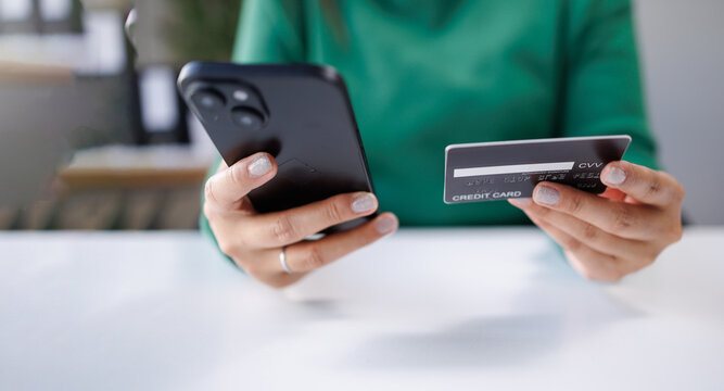 A woman holds a smartphone and a credit card while navigating payment options. This captures the essence of modern financial transactions in everyday life.