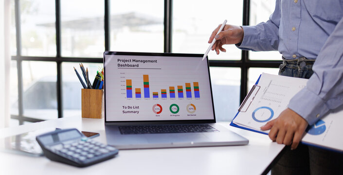 A comprehensive view of a professional reviewing a project management dashboard on a laptop, emphasizing the value of data-driven decision making in teamwork.
