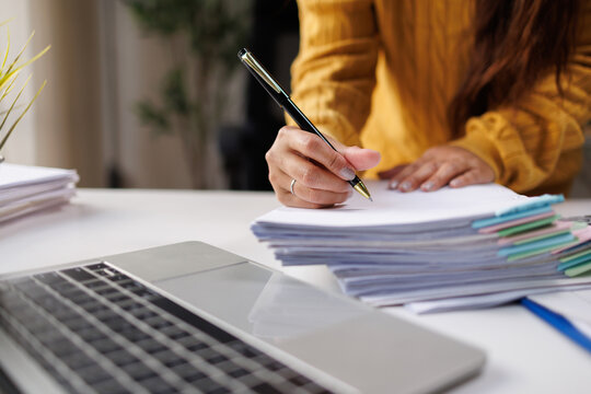 This image captures a person deeply engaged in writing, surrounded by diverse papers and a laptop, epitomizing an active creative and organizational process.
