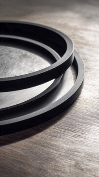 Black rubber ring on brushed aluminum plate, crisp shadow contrast on wooden table