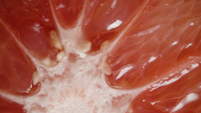 Macro rotation of the red flesh of a sliced grapefruit half.