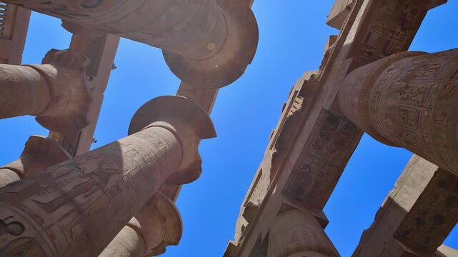 Karnak Temple in Luxor, Egypt. Monumental columns of Karnak Temple Great Hypostyle Hall tower over viewer against blue sky, Luxor Egypt.