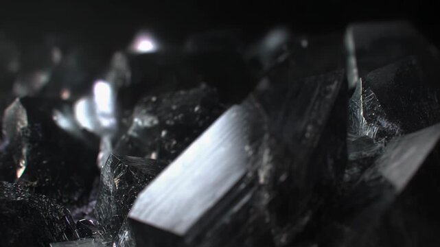 Black crystals with sharp facets and reflective surfaces creating an abstract geometric texture, highlighting strength, formation, and precious dark geology