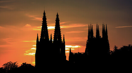 Naklejka premium Silhouette of a gothic cathedral with spires against a fiery orange sunset.