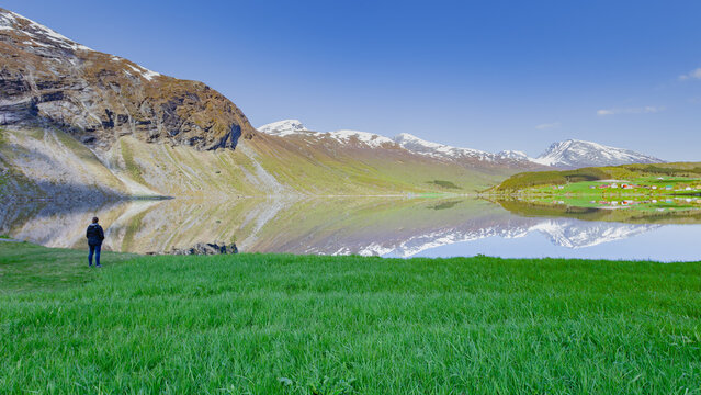 Mujer de espaldas admirando el efecto espejo en el lago Eidsvatnet en Noruega.