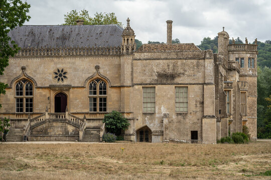 Exterior view of Lacock Abbey's south facade with its ornate windows and staircase, England