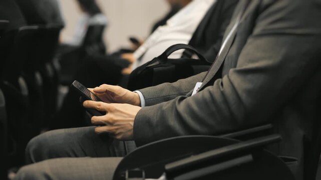 Business man using smartphone while attending conference, audience behavior and digital distraction during corporate event indoors.